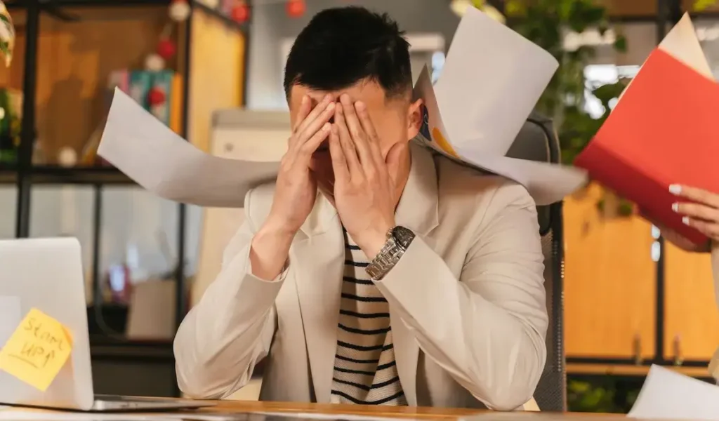 Homem exausto no escritório com sinais de burnout e stress crónico.
