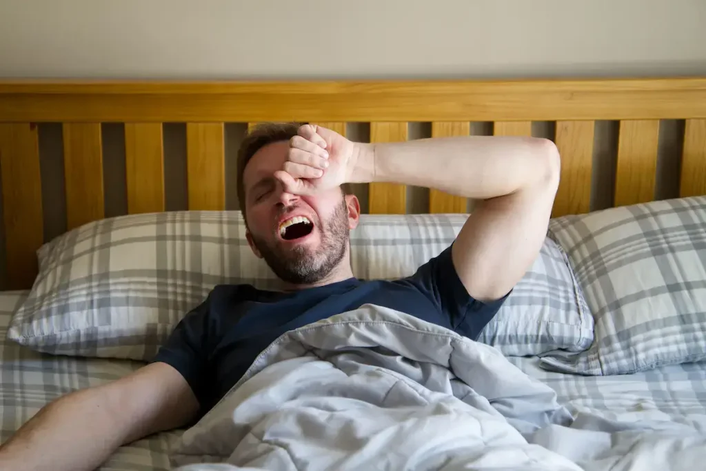 Homem a acordar cansado, mesmo depois de dormir o suficiente.